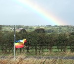 the rainbow meant the rain was dying out but the flapping of the rainbow peace flag is indicative of the strong winds