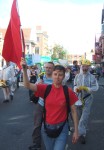 here a demonstrator with a socialist red flag followed by a group in decomination suits with one using a megaphone to say, 'Do not be alarmed, stay in your houses...'etc.