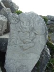 a curled figure with hand extended on a rock above the work area