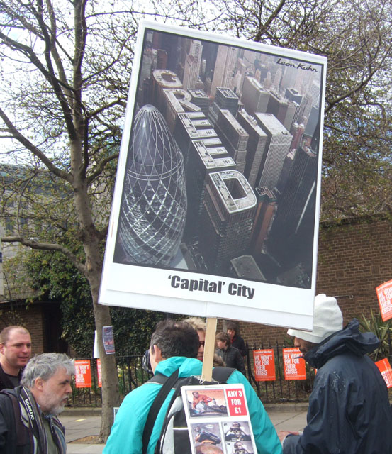 this participant was selling postcards, the copy on the placard symbolising corporate greed. this participant was selling postcards, the copy on the placard symbolising corporate greed.